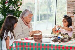 abuela enseñando su nietas cómo a hacer Navidad natividad artesanía - real familia foto