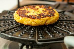 tradicional Colombiana arepa Delaware choclo preparación. maíz panes siendo asado en un redondo parrilla foto