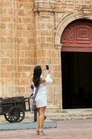 Beautiful woman taking pictures of the San Pedro Claver church located in the walled city of Cartagena de Indias photo