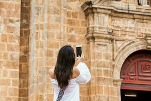 Beautiful woman taking pictures of the San Pedro Claver church located in the walled city of Cartagena de Indias photo