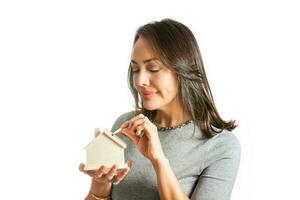 Young beautiful woman saving for a new house isolated on white background photo