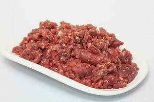 Closeup of a dish full of ground beef isolated on white background. Preparation of a baked egg and vegetables stuffed meatloaf covered with bacon. Meat roll photo