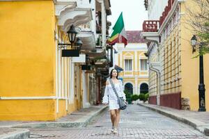 Beautiful woman on white dress walking alone at the streets of the colonial walled city of Cartagena de Indias photo