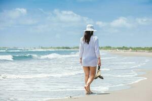 mujer caminando a un vacío paradisíaco tropical playa en un hermosa soleado día foto