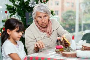 Grandmother teaching her granddaughter how to make christmas Nativity crafts - Real family photo