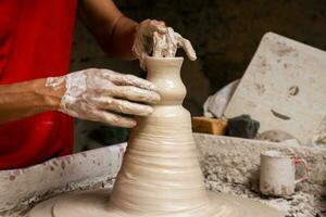 Man making ceramic articles on the potters wheel in a traditional factory in the city of Raquira located in the department of Cundinamarca in Colombia photo