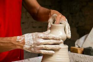 Man making ceramic articles on the potters wheel in a traditional factory in the city of Raquira located in the department of Cundinamarca in Colombia photo