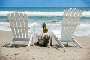 Empty white wooden chairs at a paradisiac beach on the tropics in a beautiful sunny day photo