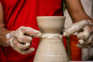 Man making ceramic articles on the potters wheel in a traditional factory in the city of Raquira located in the department of Cundinamarca in Colombia photo