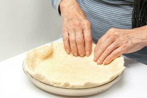 Giving shape to the quiche Lorraine dough into the glass baking dish photo