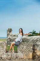 Beautiful woman on white dress sitting alone at the walls surrounding the colonial city of Cartagena de Indias photo