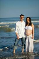 Couple at the beach waiting for their baby - 28 weeks photo