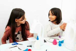 Two young girls making a toy microscope with recyclable material photo