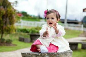 dulce uno año antiguo bebé niña jugando al aire libre. canto contento al aire libre. foto