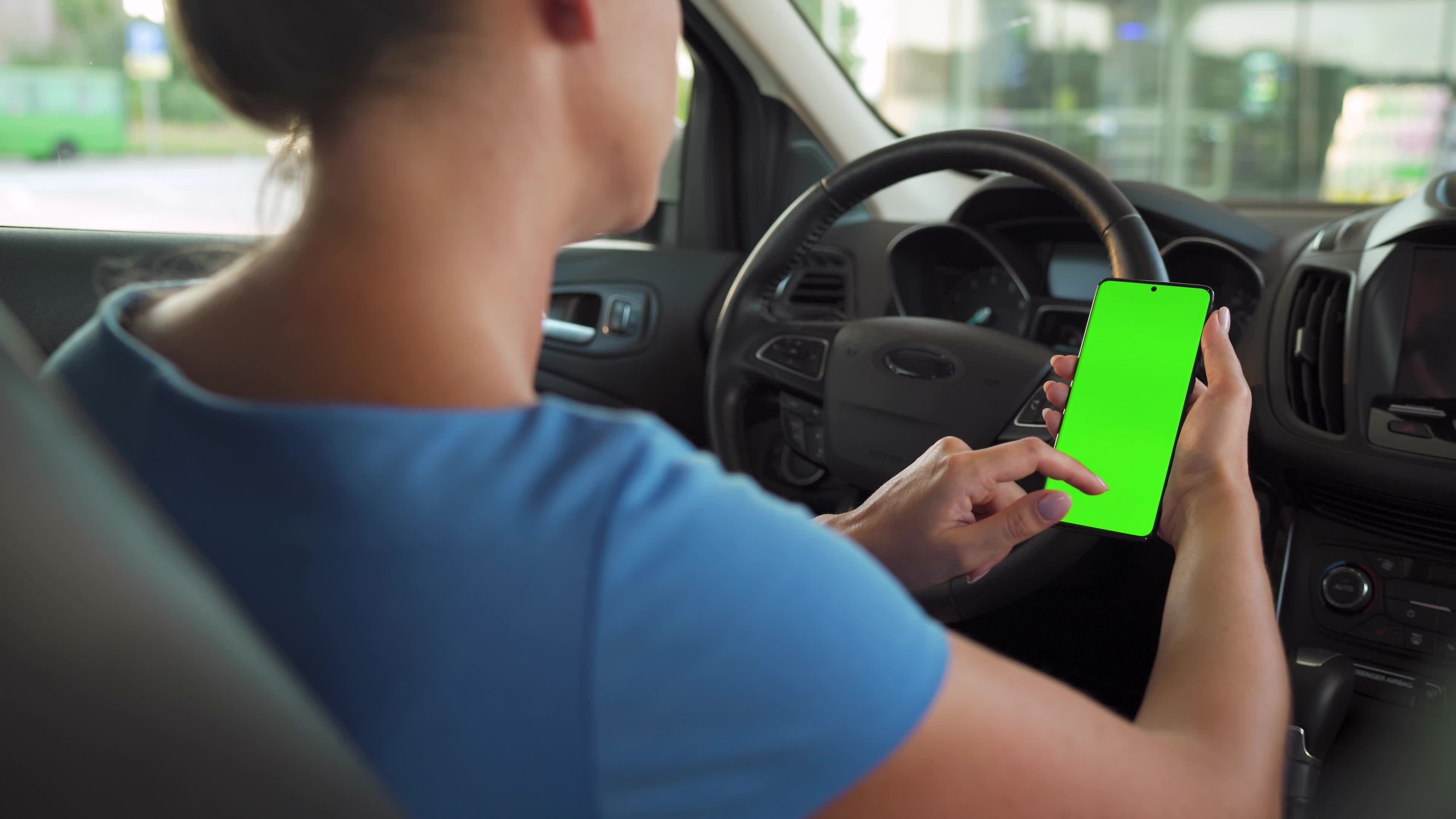 Female driver using a smartphone inside the car. Chromakey smartphone
