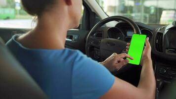 Female driver using a smartphone inside the car. Chromakey smartphone with green screen. Auto navigation. Internet addiction. Automobile insurance application. video