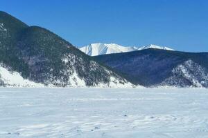 Baikal mountains in winter in snow. Forest in snow covered mount photo