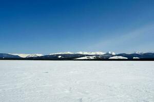 Baikal mountains in winter in snow. Forest in snow covered mount photo