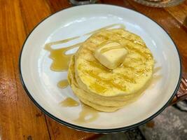 apilar de llanura panqueques con mantequilla y miel en un blanco pila de platos de llanura panqueques con mantequilla y miel en un blanco plato foto