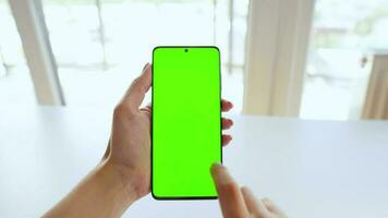 kvinna händer använder sig av en smartphone med en grön skärm i vertikal läge närbild. krom nyckel. pOV video