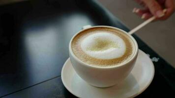 4k girar video, Fresco caliente latté en cerámico blanco taza con fumar en café o restaurante .bebida Mañana concepto. bebida de café con cremoso Leche en antiguo de madera plato video