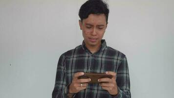 Young man Indonesian are playing mobile game with happiness and disappointed. The video is suitable to use for expression video promote and mobile game advertising.