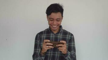 giovane uomo indonesiano siamo giocando mobile gioco con felicità e deluso. il video è adatto per uso per espressione video promuovere e mobile gioco pubblicità.