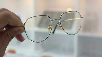 närbild av hand innehav glasögon i optisk affär, hand innehav glasögon video