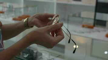 Closeup of hand holding eyeglasses in optical shop, hand holding glasses video