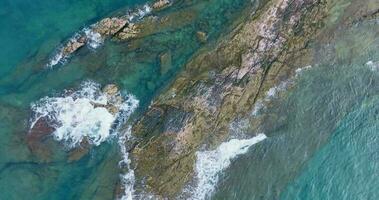 aéreo zumbido ver de el rocoso línea costera con claro turquesa mar video