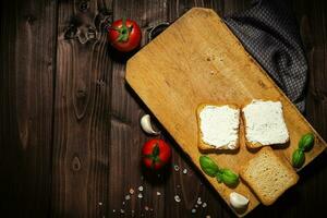 Breakfast photo of cream cheese and bread sliced. Tomato on wooden background.