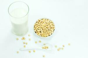 A glass of soy milk with soy beans on spoon on white background photo