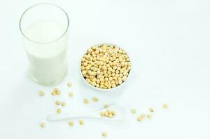 A glass of soy milk with soy beans on spoon on white background photo