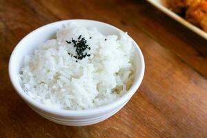 Rice in white cup on wood background and black sesame photo