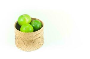 fresh green limes in the bamboo basket isolated on white background,Closeup shoot, Select focus photo