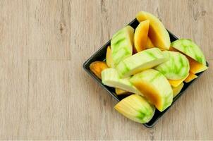 mango,maduro mangos Listo a comer en negro plato en woonden antecedentes foto