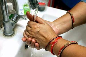 recortado imagen de un asiático mujer Lavado manos en lavabo a hogar. selectivo atención foto