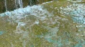 el presión de agua caídas desde el Roca cascada y formas blanco espuma. video