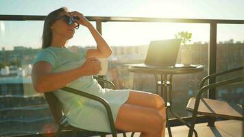 mujer bebidas café y descansa durante un descanso en el balcón en contra el el ajuste Dom. remoto trabajo concepto video