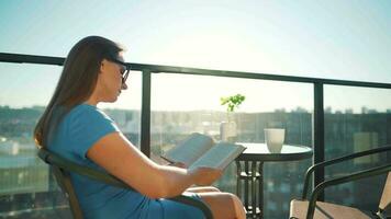 femme séance sur le balcon et en train de lire une livre à le coucher du soleil video