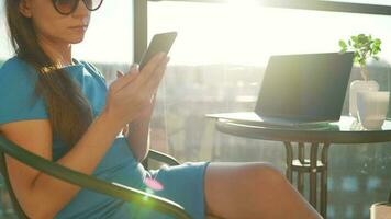 Woman using smartphone on the balcony against the backdrop of the sunset. Outdoor home office. Remote work concept video