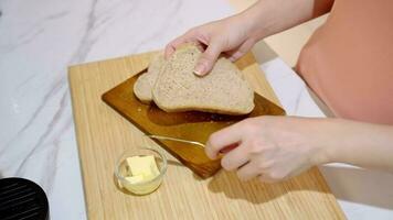 4k video, crema burro su totale Grano pane. coltello diffusione vegano burro su Sandwich prima colazione. imbrattando burro diffusione su appena al forno fetta di pane. preparare culinario prima colazione video