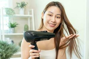 Hair Dryer, beautiful happy, asian young woman, girl hand in using, holding hairdryer to dry, blowing blonde long straight after shower at home. Hairdressing, hair treatment isolated on background. photo