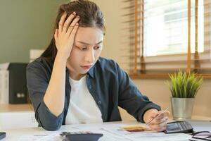 Financial owe, hand of asian woman sitting, holding many credit card, stressed  by calculate expense from invoice or bill, no money to pay, mortgage or loan. Debt, bankruptcy or bankrupt photo