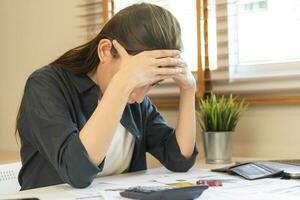 Financial owe asian woman sitting cover face with hands, stressed by calculate expense from invoice or bill, have no money to pay, mortgage or loan. Debt, bankruptcy or bankrupt concept. photo