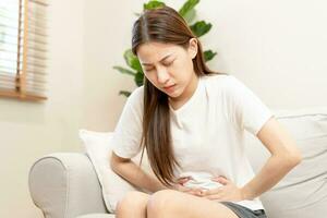 Flatulence asian young woman, girl hand in stomach ache, suffer from food poisoning, abdominal pain and colon problem, gastritis or diarrhoea. Patient belly, abdomen or inflammation, concept. photo