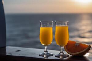 Two glasses of orange juice in front of a sea background, photo