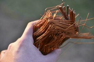 A bundle of copper wire in his hand. Copper scrap. Shiny red copper wire. photo