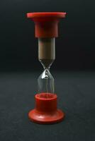 Glass hourglass on a black background. Multicolored glass hourglass. photo