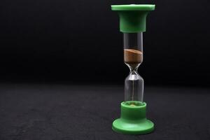 Glass hourglass on a black background. Multicolored glass hourglass. photo